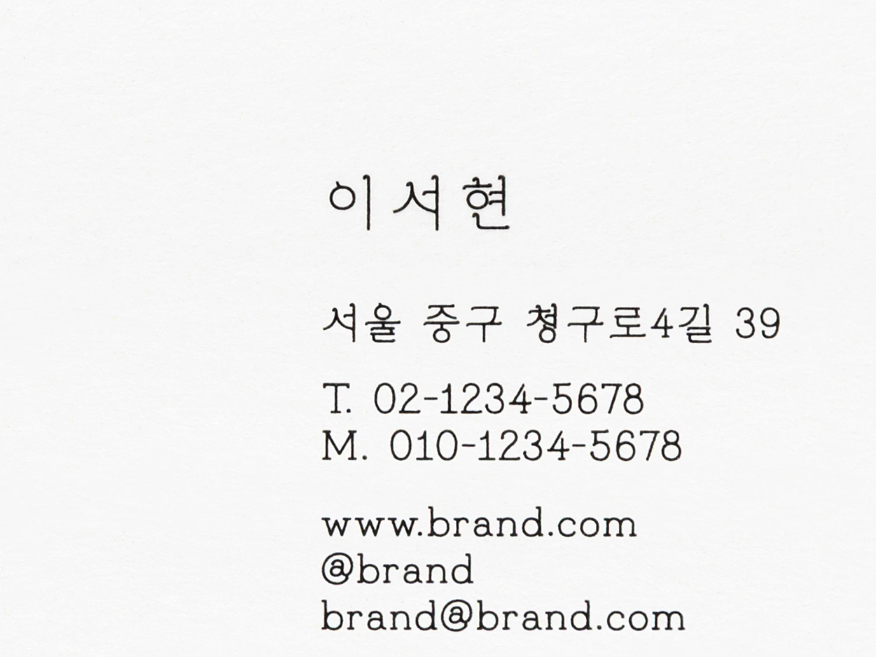 흰색 명함에 검정으로 인쇄된 이름·주소·전화번호 글자 접사