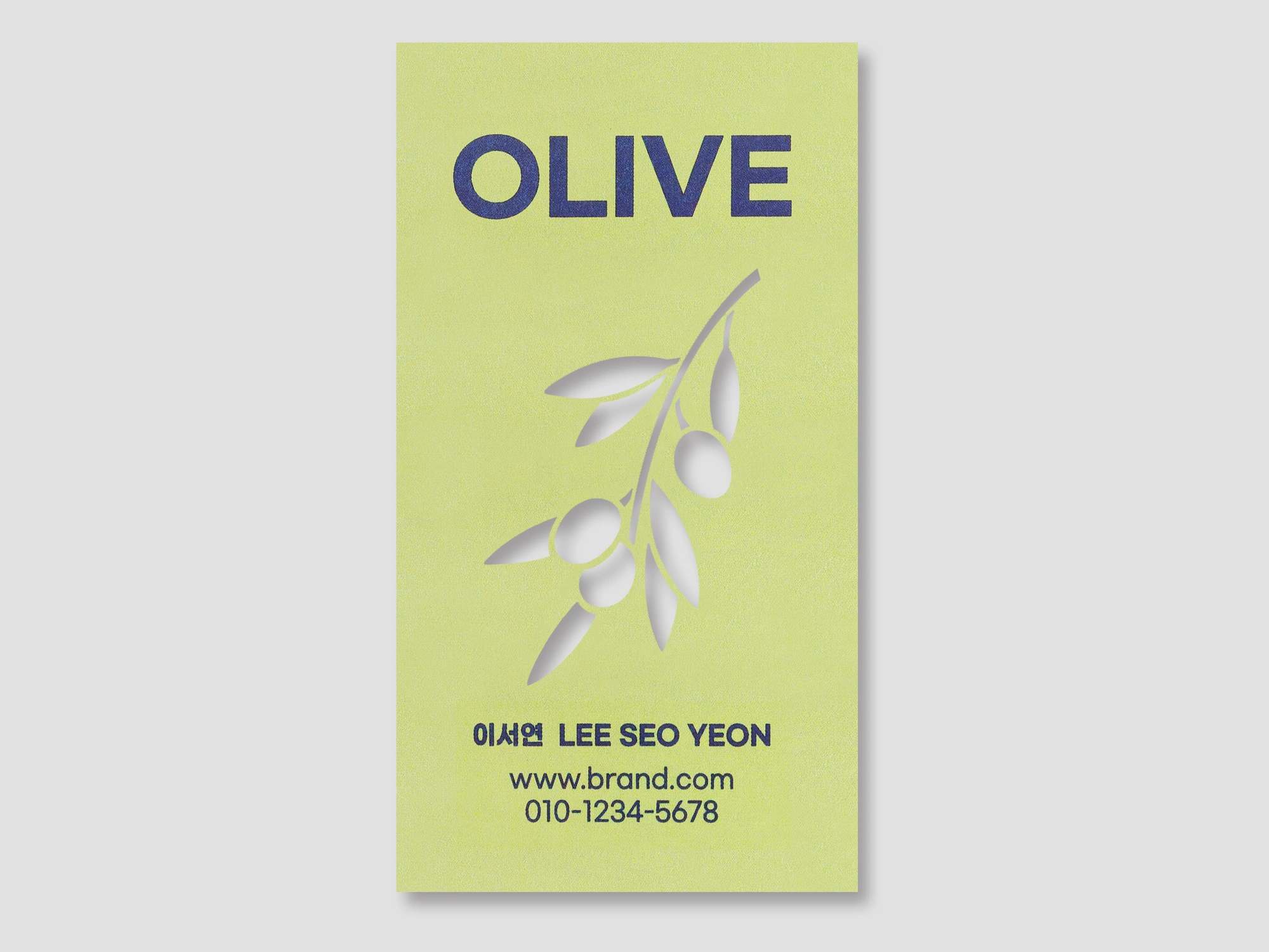 연두색 세로 명함의 올리브 잎 모양을 레이저로 비워낸 정면 사진